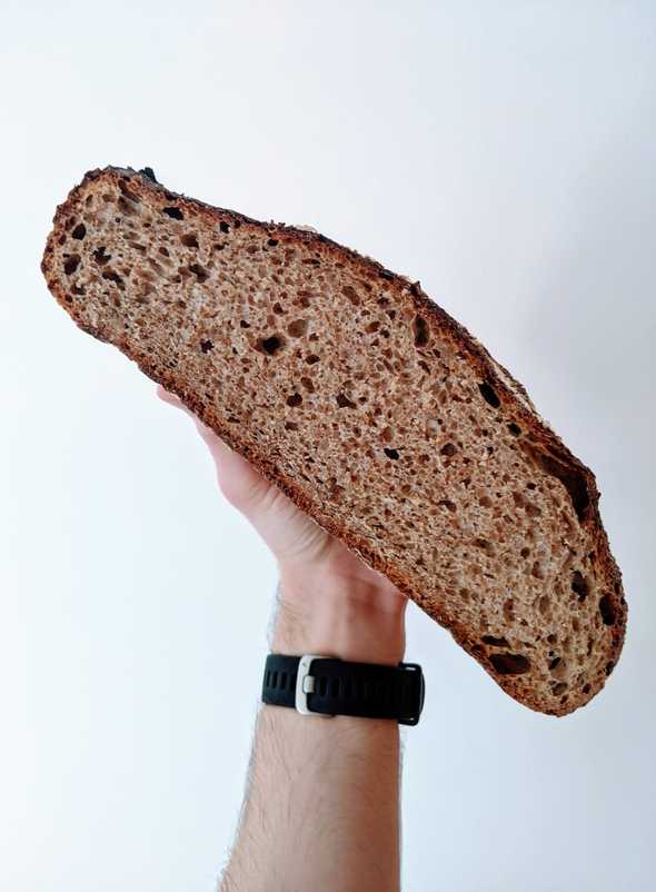 A hand holding half a loaf, showing the interior crumb